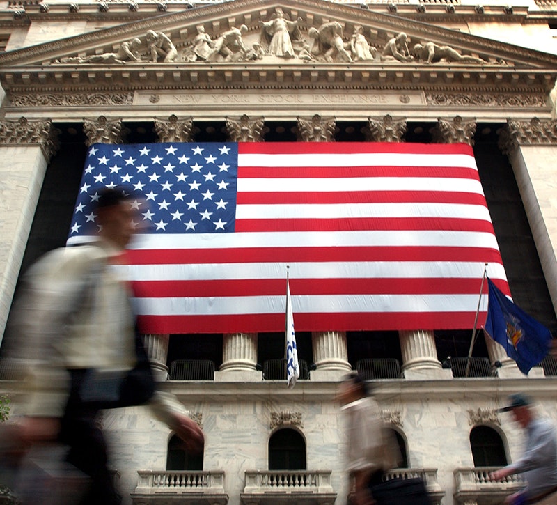 Fast Moving crowd walking by a huge American flag hung outside the New York Stock Exchange