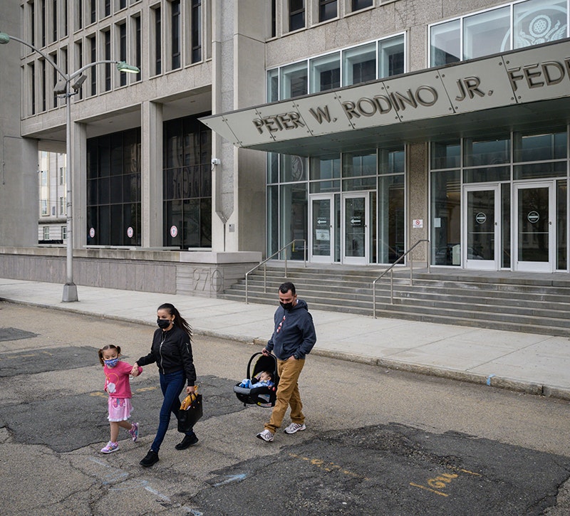 A family (parents and two small children) are seen leaving an Immigration and Customs Enforcement (ICE) office building after an initial check-in.
