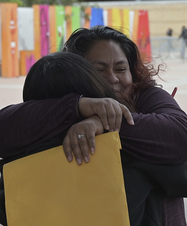 A woman embraces a child while holding a file folder