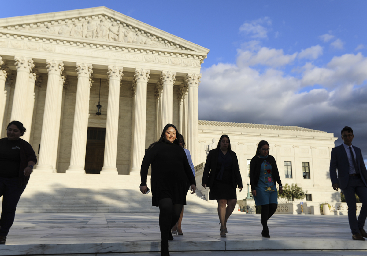 A group of people walk down the steps of the Supreme Court.