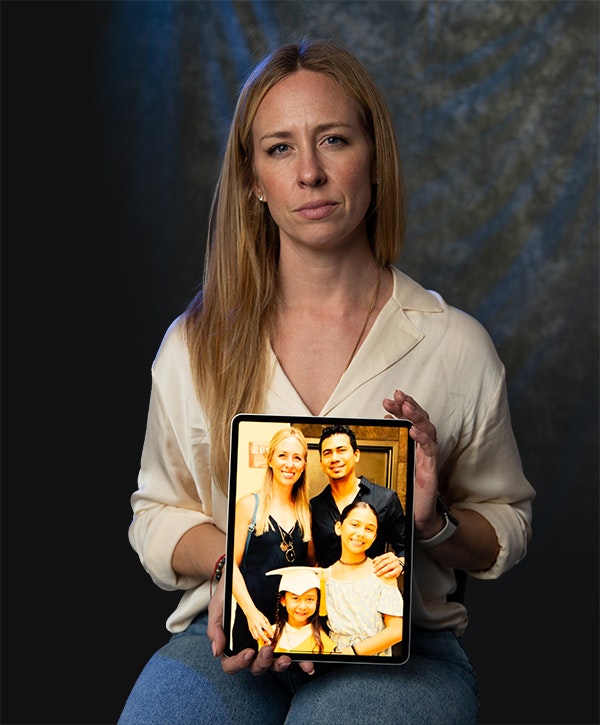A woman holds a tablet displaying a photo of her family