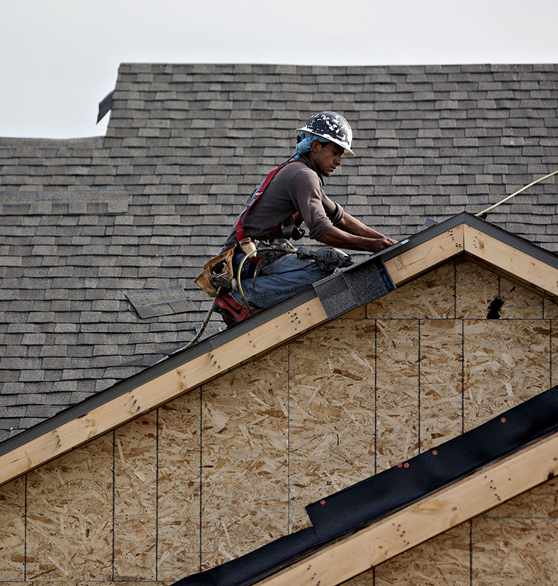 A worker installs shingles during construction at the Williston Apartments luxury development in Williston, North Dakota, U.S.,