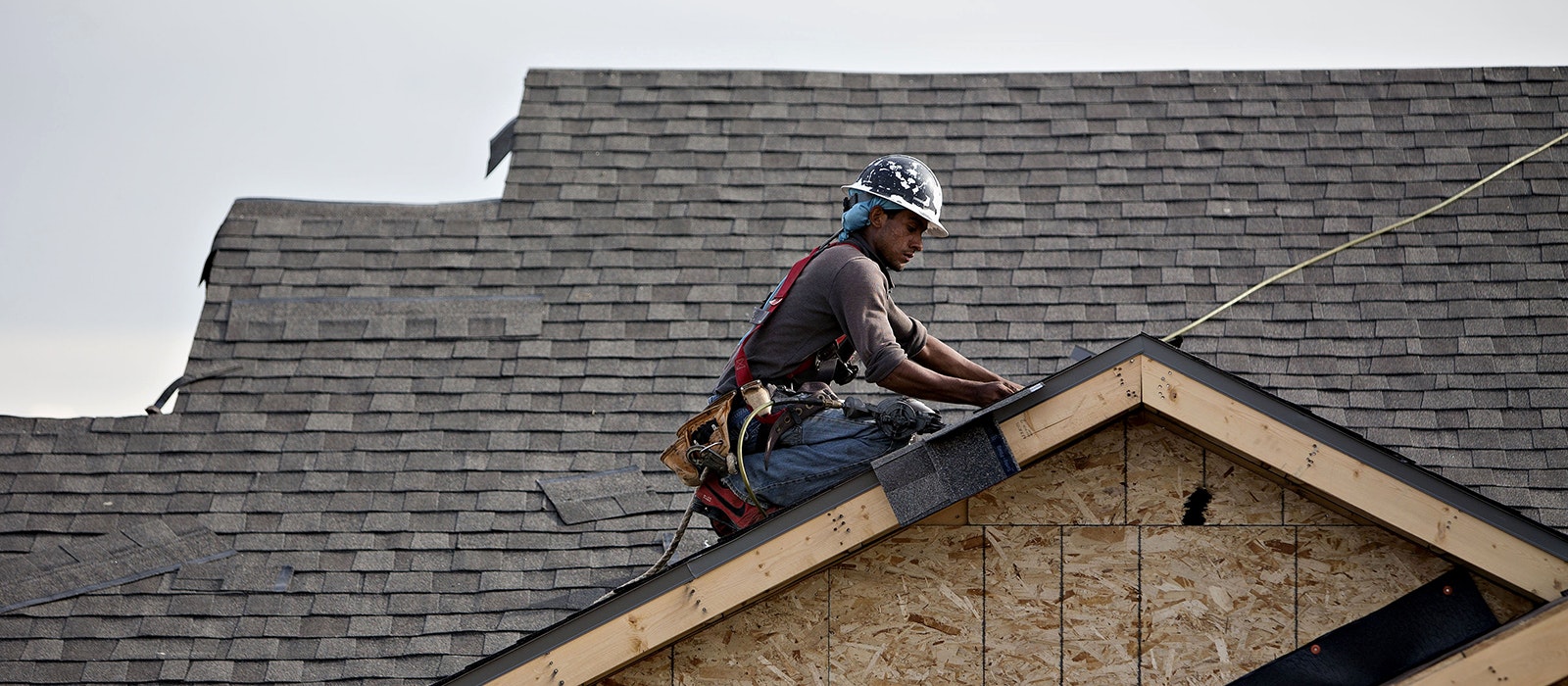 A worker installs shingles during construction at the Williston Apartments luxury development in Williston, North Dakota, U.S.,