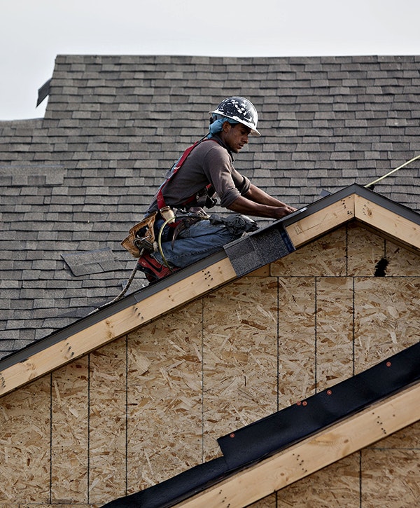 A worker installs shingles during construction at the Williston Apartments luxury development in Williston, North Dakota, U.S.,