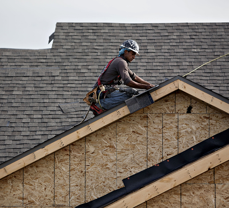A worker installs shingles during construction at the Williston Apartments luxury development in Williston, North Dakota, U.S.,